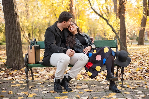 Amoureux heureux jeune couple assis sur un banc dans le parc d'automne