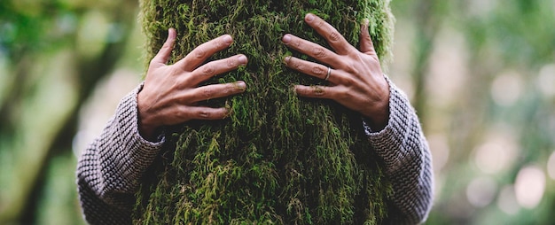 Photo amoureux de la nature étreignant l'arbre du tronc avec du musc vert dans la forêt de bois tropicaux. fond naturel vert. le concept des gens aiment la nature et se protègent de la déforestation, de la pollution ou du changement climatique