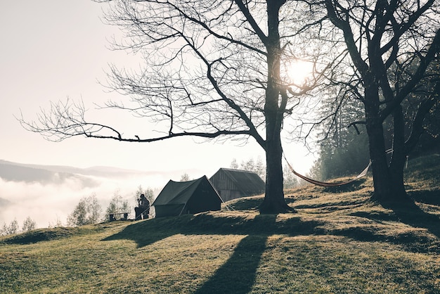 Amoureux de la nature. Jeune homme assis près de la tente en camping dans les montagnes