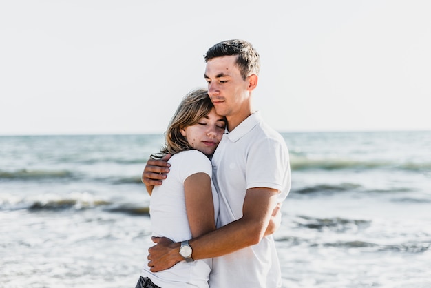 Les amoureux près de l'océan s'étreignent et s'amusent. mari et femme embrassent au coucher du soleil près de la mer. amoureux en vacances. repos d'été. promenade romantique au bord de l'océan