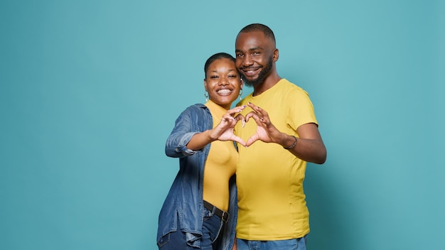 Les amoureux de la publicité en forme de coeur signe avec les mains devant la caméra. Couple affectueux faisant un symbole romantique et intime, montrant un geste d'affection, de romance et de sentiments.