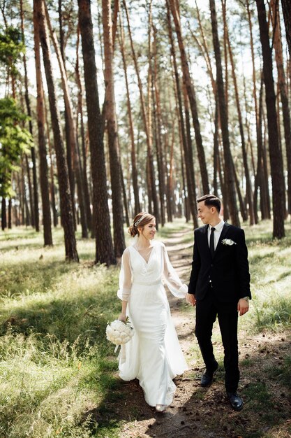 Les amoureux s'embrassent dans la nature. la mariée et le marié se promènent dans la forêt. couple de mariage