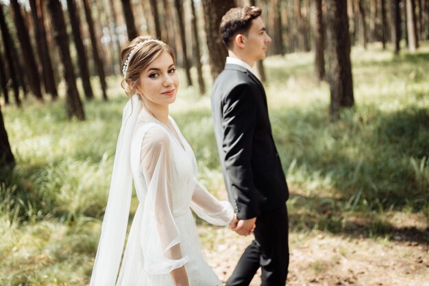 Les amoureux s'embrassent dans la nature. la mariée et le marié se promènent dans la forêt. couple de mariage