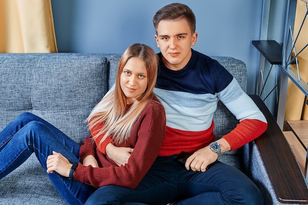 Les amoureux sont assis sur un canapé dans le dortoir d'université.