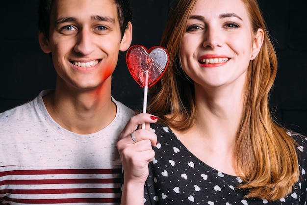 Amoureux souriants avec une sucette en forme de cœur