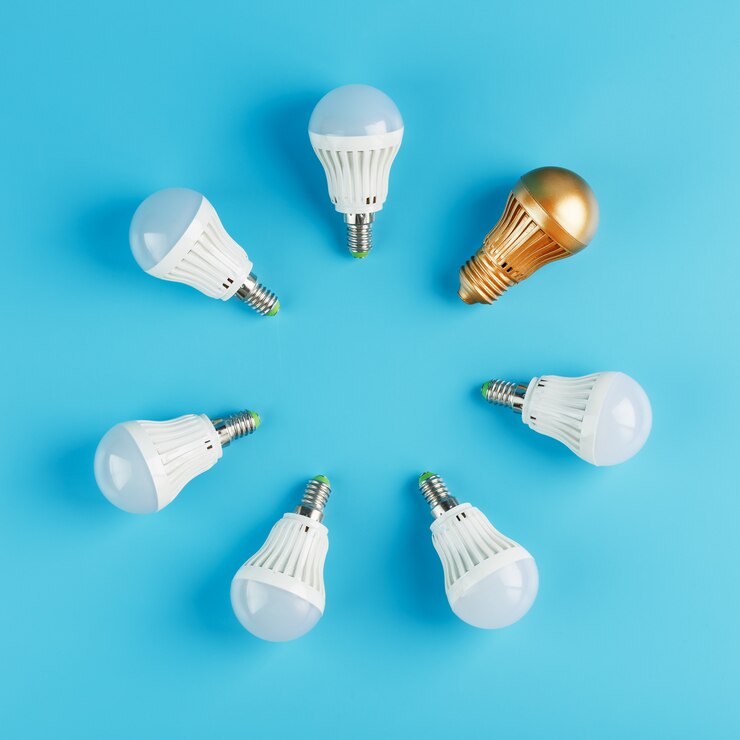 Photo une ampoule dorée se détache dans le cercle des ampoules d'un anneau de lampes blanches sur un mur bleu.