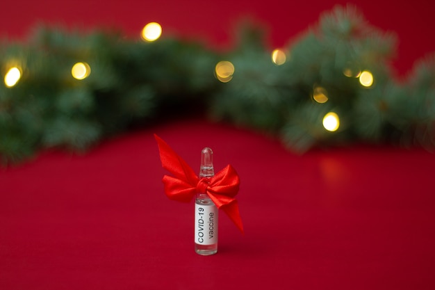 Ampoule du vaccin COVID-19 près de l'arbre de Noël