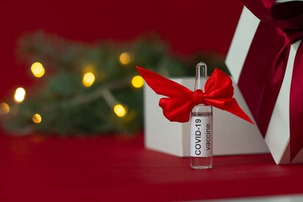 Ampoule du vaccin COVID-19 près de l'arbre de Noël