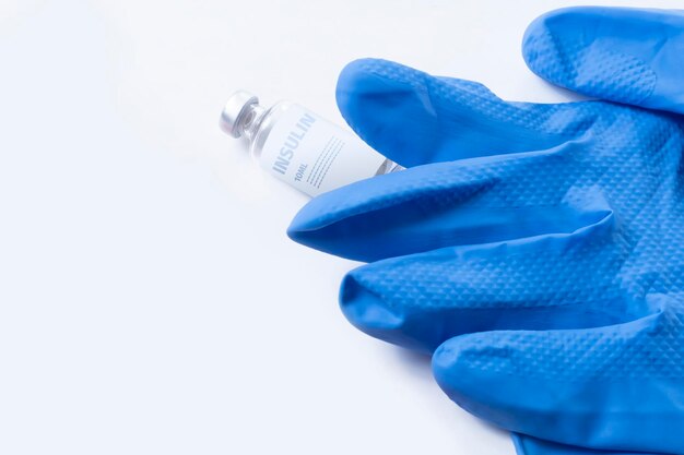 Ampoule d'insuline et gants médicaux isolés sur un fond blanc
