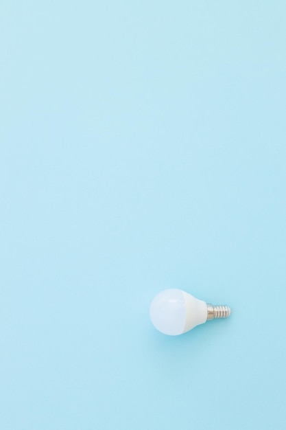 L'ampoule LED se trouve sur un fond bleu pastel Concept d'économie d'énergie Vue de dessus du minimalisme