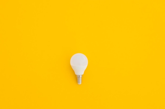 L'ampoule LED se trouve sur un fond jaune pastel Concept d'économie d'énergie Vue de dessus du minimalisme