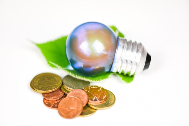 Photo ampoule avec la lumière de la lampe avec feuille verte et pièce sur fond blanc - idée d'économie d'énergie, économie d'énergie et le concept du monde
