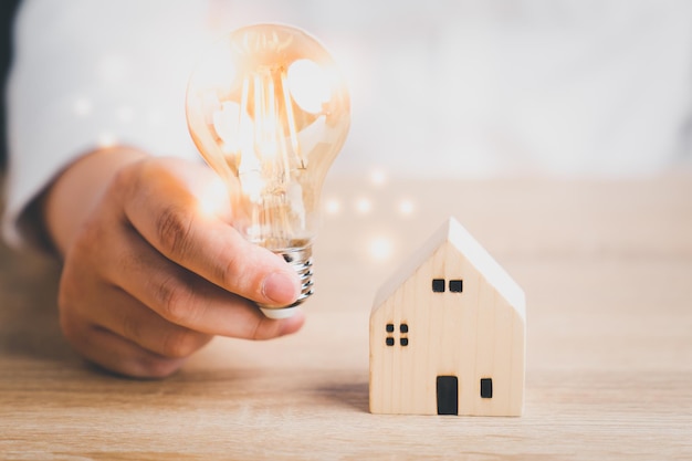 Photo ampoule avec maison en bois sur la table un symbole pour la construction