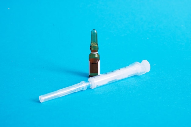 Ampoule avec médicament et seringue sur fond bleu