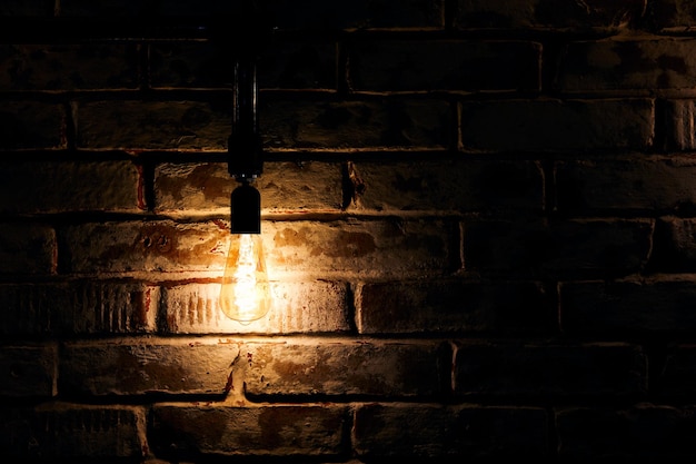L'ampoule rougeoyante lumineuse accroche près du vieux mur de briques grunge