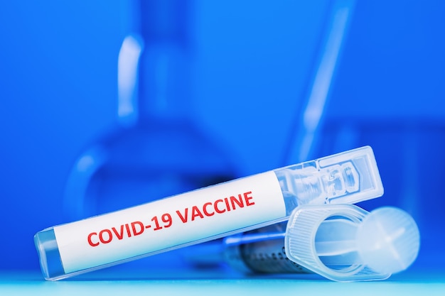 Photo ampoule avec un vaccin contre le coronavirus covid19 sur un bleu