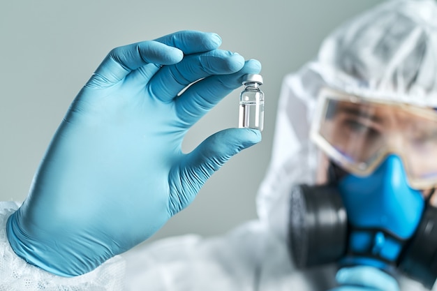 Ampoule avec un vaccin entre les mains d'un virologue