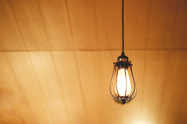 Photo ampoule vintage edison accroché sur un fond en bois au café.