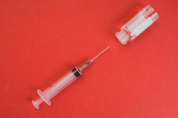 Ampoules médicales et seringue sur fond rouge