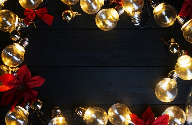 Ampoules et poinsettias rouges sur bois noir. Vue de dessus, espace de copie