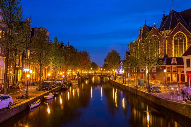 AMSTERDAM, PAYS-BAS - 2 mai 2107: L'église traditionnelle appelle The Oude Kerk où les touristes de la zone de la tour de construction visitent au crépuscule.