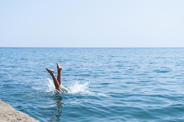 Amusant au bord de la mer, l'enfant saute à l'eau, plonge dans l'eau de l'océan. Éclaboussures d'eau. jeux de plage.