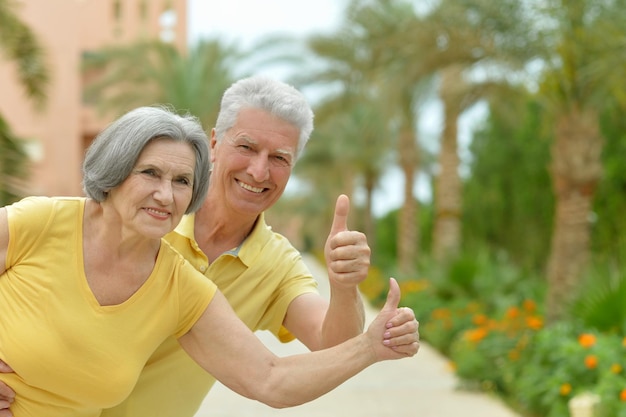 Amusant couple de personnes âgées souriant avec les pouces vers le haut en vacances