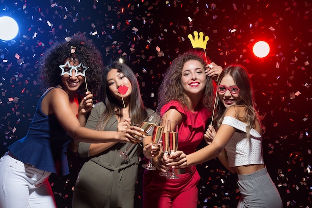 Amusant à La Fête Du Nouvel An. Femmes Heureuses Célébrant Et Posant Avec Des Accessoires Photo Et Du Champagne