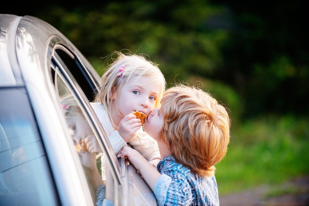 Amusant petit couple disant au revoir avant le voyage en voiture adieu concept enfant petit garçon donne baiser fo