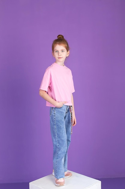 Amusante fille positive en jeans et un t-shirt riant grimaçant en regardant la caméra isolée sur fond violet Heureux enfant européen étudiant closeup portrait