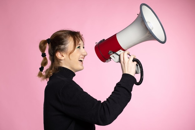 Amusante jeune femme criant à travers un mégaphone jeune femme utilisant un haut-parleur sur des arrière-plans colorés