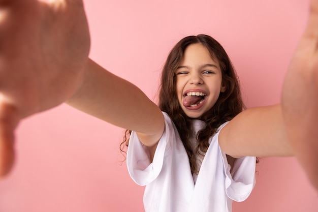 Amusante petite fille prenant un selfie et montrant la langue du point de vue de la photo