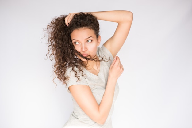 Amusante et positive jeune femme jouant avec des cheveux bouclés