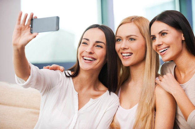 amusement au point. trois belles jeunes femmes faisant selfie et souriant