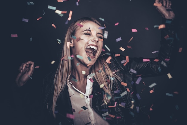 Amusement de confettis. Belle jeune femme jetant des confettis et semblant heureuse