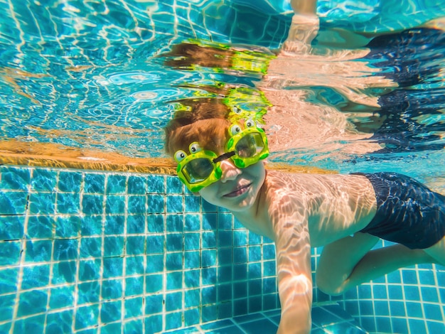 Amusement sous-marin de jeune garçon dans la piscine avec des lunettes d'amusement de vacances d'été