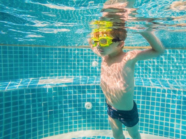 Amusement sous-marin de jeune garçon dans la piscine avec des lunettes d'amusement de vacances d'été