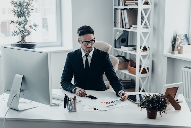 Analyse des données. Beau jeune homme en costume complet travaillant avec des documents