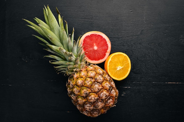 Ananas et agrumes sur fond de bois Fruits tropicaux et noix Vue de dessus Espace libre pour le texte