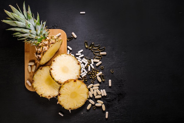 Ananas coupé en tranches avec des bourgeons de pilules bio sur fond noir