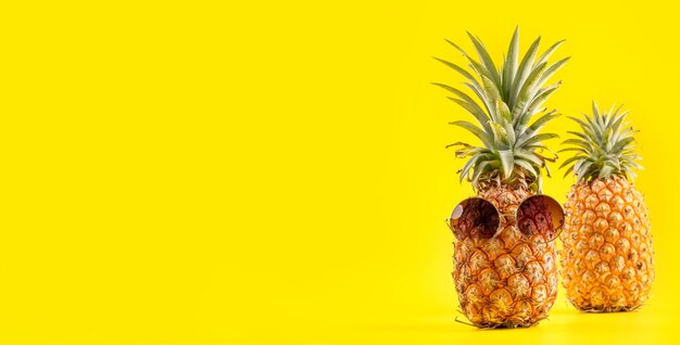 Ananas créatif à la recherche avec des lunettes de soleil et shell isolé sur fond jaune, copie espace close up