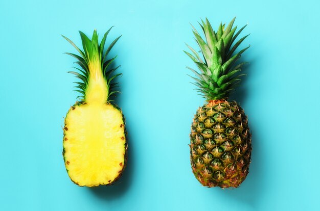 Ananas entier et fruits à moitié tranchés sur bleu