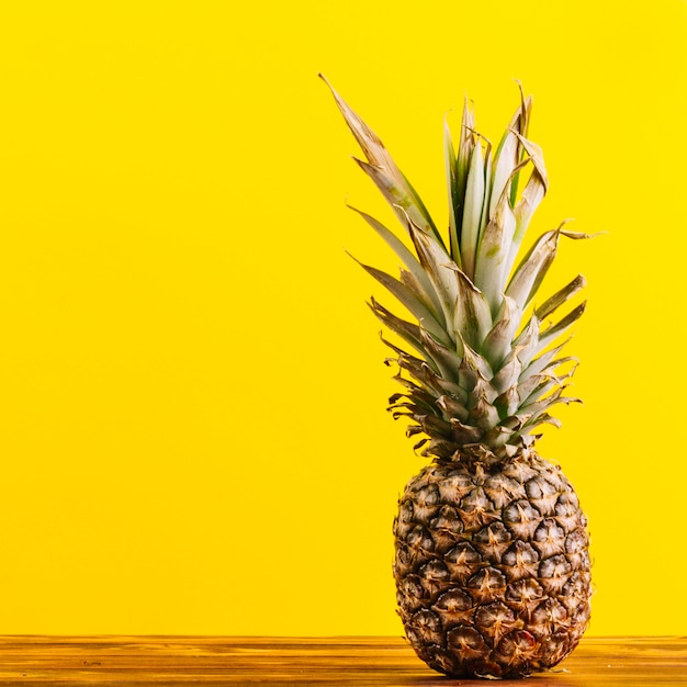 Ananas entier sur la table sur fond jaune