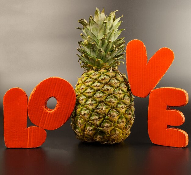 Ananas entouré de lettres d'amour volumétriques sur fond noir.