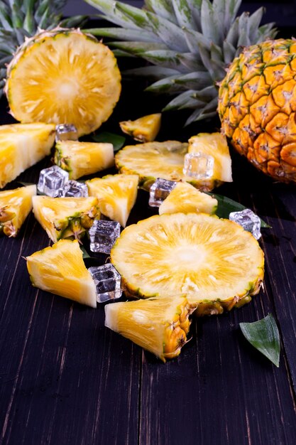 Ananas frais sur bois noir, fond noir.