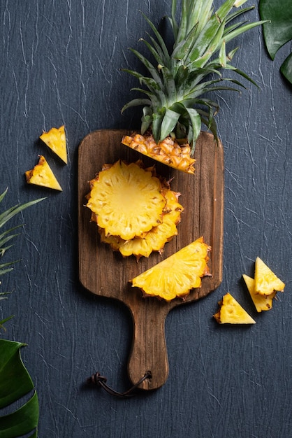 Ananas frais coupé avec des feuilles tropicales sur fond bleu foncé