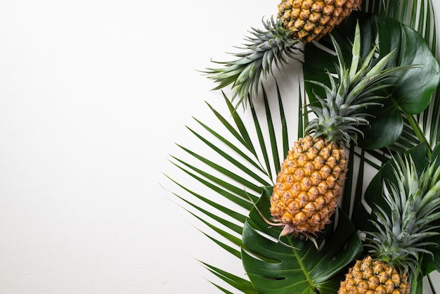 Ananas frais avec des feuilles tropicales sur fond blanc