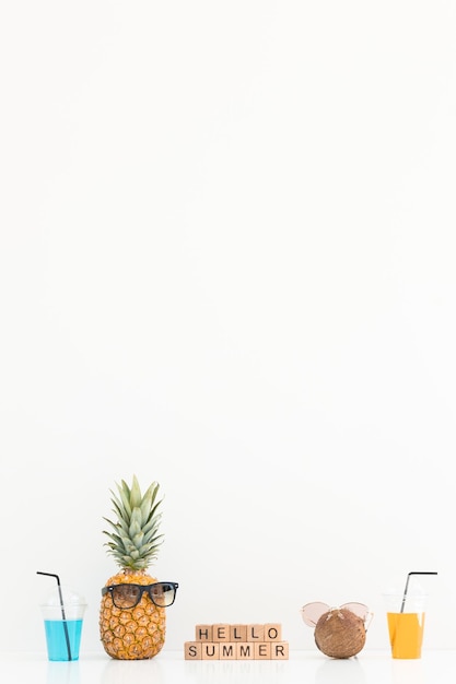 Ananas frais et noix de coco avec des lunettes de soleil sur fond de couleur Bonjour l'été