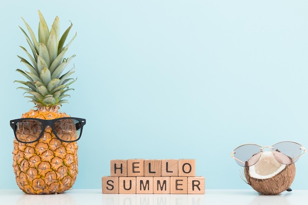 Ananas frais et noix de coco avec des lunettes de soleil sur fond de couleur Bonjour l'été