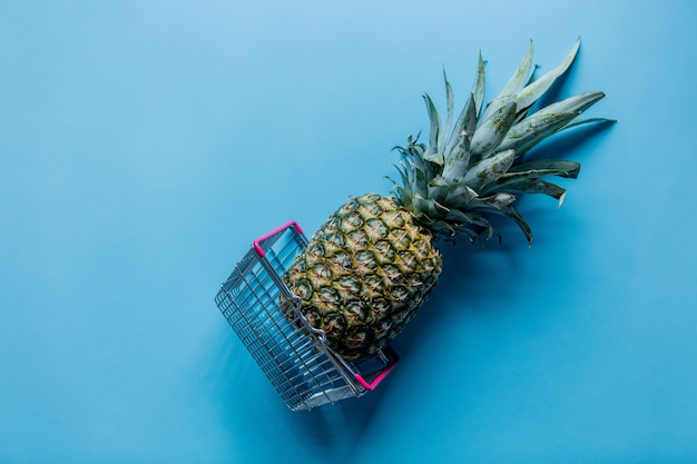 Ananas frais avec panier sur fond bleu.